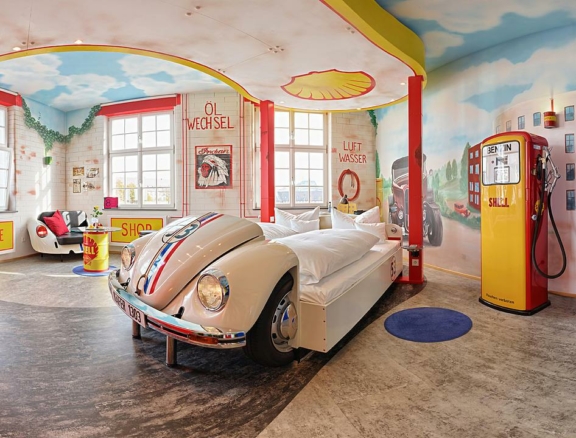 VW-Käfer "Herbie" als Bett im Themenzimmer "Tankstelle" (V8-Hotel in der Motorworld Region Stuttgart auf dem Flugfeld Böblingen/Sindelfingen; Foto: V8-Hotel/Frank Hoppe)